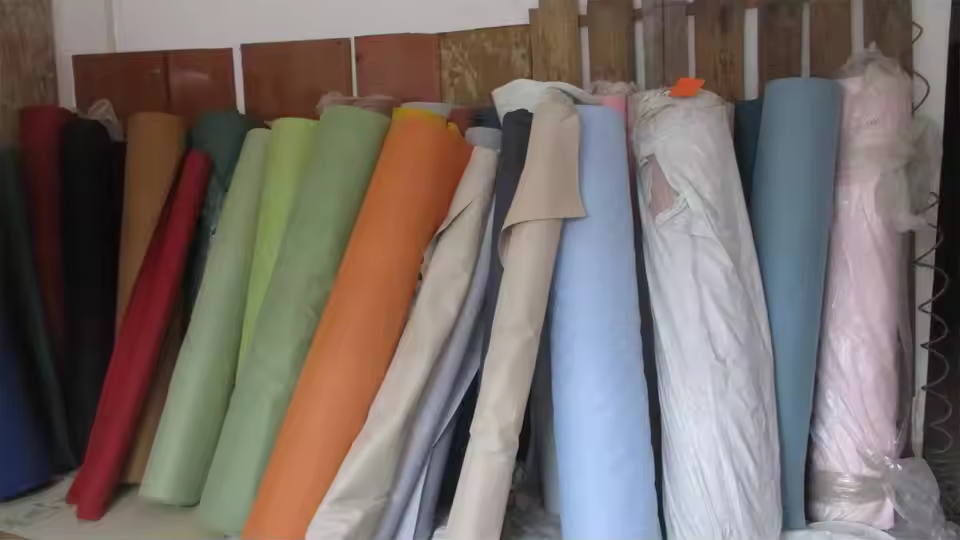 Fabric and leatherette material rolls in a packaging factory — materials used for premium hair accessory box wrapping and satin interiors