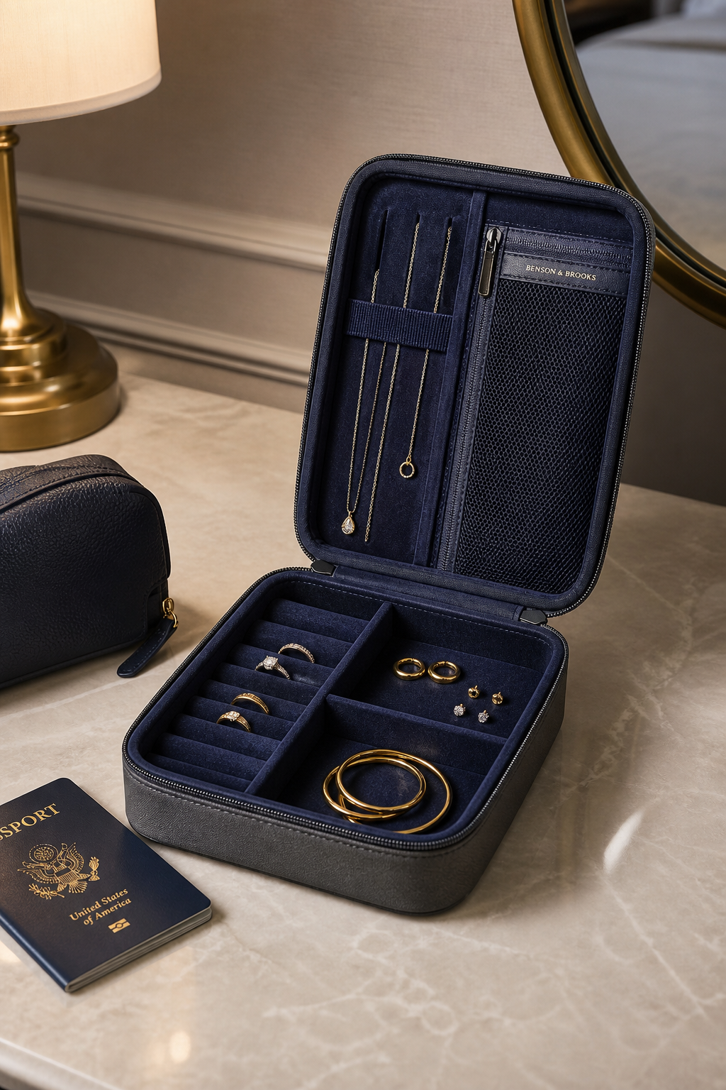 Open EVA hard-shell travel jewelry case with necklace channel, ring slots, earring wells, and zippered mesh pocket on a hotel vanity